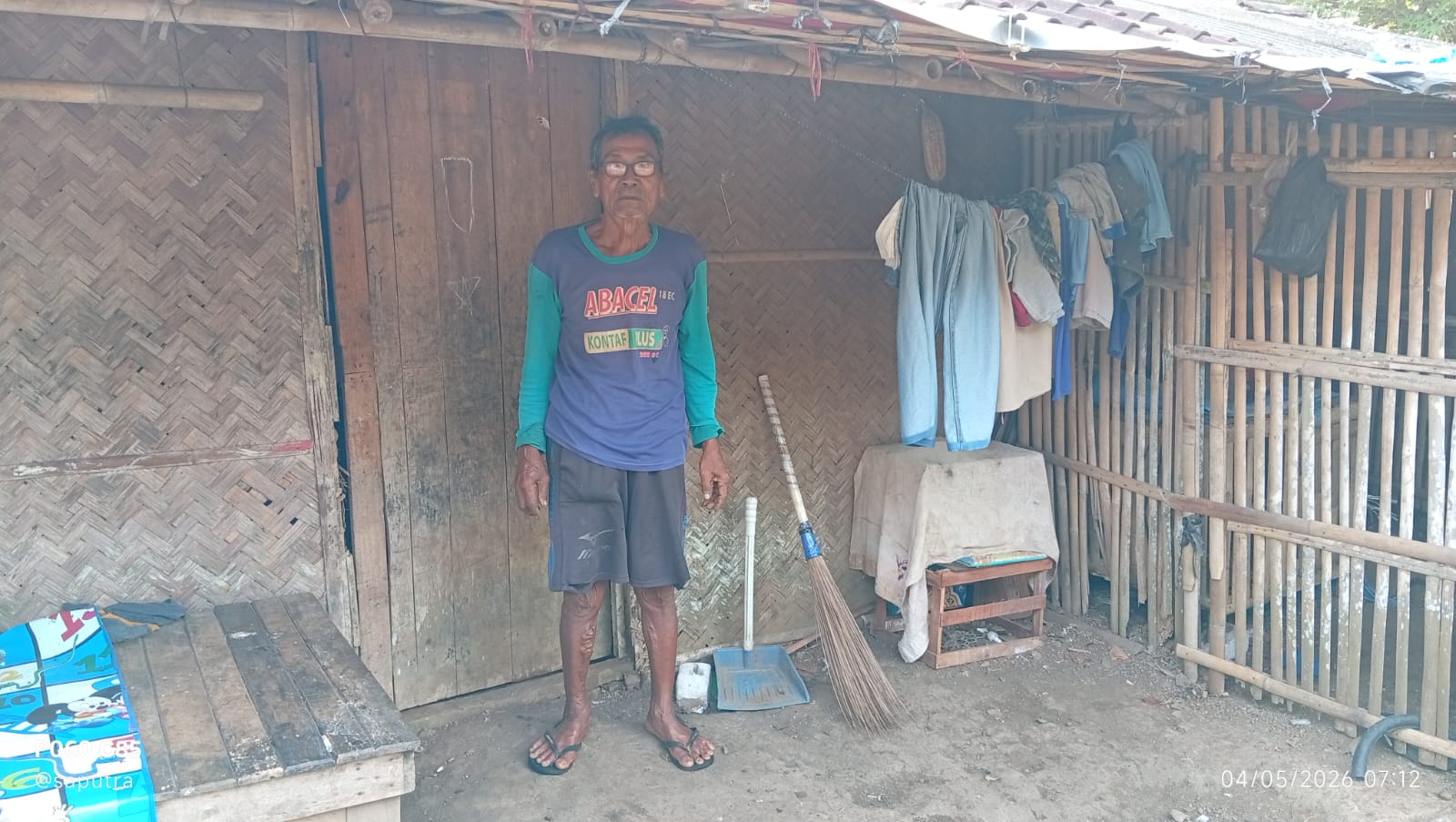 Caption : Abah Dasum berdiri di depan rumahnya yang nyaris roboh di Dusun Krajan RT 006/RW 002, Desa Pasirmukti, Kecamatan Telagasari, Kabupaten Karawang. Kondisi rumah berdinding bilik bambu dan atap rapuh tersebut sudah lama ditempati bersama keluarganya di tengah keterbatasan ekonomi