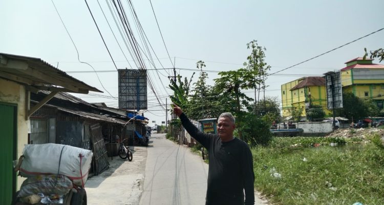 Caption : Kepala Dusun Warudoyong Utara, Muktar, menunjukkan kondisi kabel jaringan telekomunikasi yang menjuntai rendah dan semrawut di RT 33/RW 07, Desa Rengasdengklok Selatan, Kecamatan Rengasdengklok, Kabupaten Karawang. Warga meminta pihak terkait segera melakukan penataan dan perbaikan karena dinilai berpotensi membahayakan keselamatan pengguna jalan dan masyarakat sekitar. (Foto: Patriotjabar.com/Mir)
