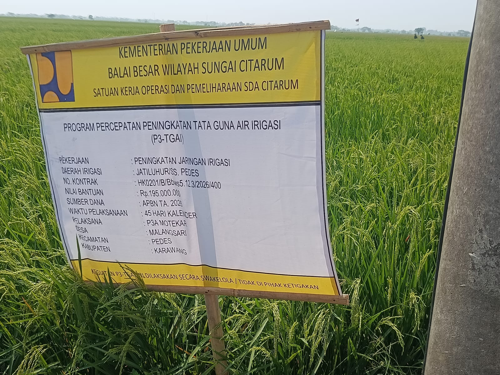 Caption : Papan informasi Program Percepatan Peningkatan Tata Guna Air Irigasi (P3-TGAI) di Desa Malangsari, Kecamatan Pedes, Kabupaten Karawang. Proyek peningkatan jaringan irigasi tersebut memiliki nilai anggaran sebesar Rp195 juta yang bersumber dari APBN Tahun Anggaran 2026, dengan pelaksana P3A Motekar dan tercantum dilaksanakan secara swakelola serta tidak boleh dipihakketigakan. Program ini kini menjadi sorotan menyusul munculnya dugaan ketidaksesuaian dalam pengelolaan anggaran material proyek.
