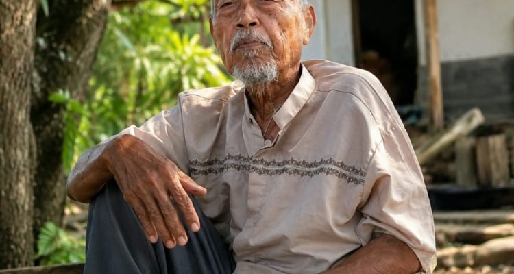 Caption: Pak Sarkom (86), seorang petani sederhana yang dikenal memiliki wawasan luas dan pemikiran mendalam, berpose di kediamannya. Meski menjalani kehidupan sederhana, semangatnya dalam belajar, berdiskusi, dan membagikan ilmu pengetahuan menjadikannya sosok inspiratif yang dijuluki sebagai "mutiara terpendam" bagi masyarakat.