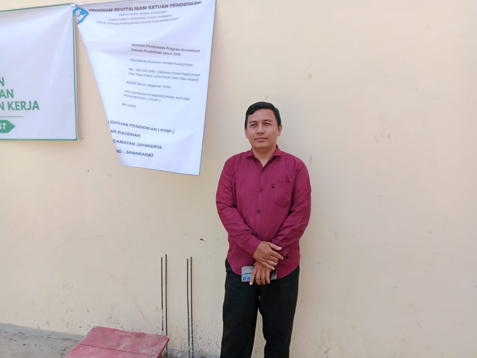 Caption : Kepala Sekolah PAUD Ar Raudhah, Rohmat, S.Pd., berfoto di depan papan informasi Program Revitalisasi Satuan Pendidikan Tahun 2026 di Desa Jayamakmur, Kecamatan Jayakerta, Kabupaten Karawang. Program bantuan pemerintah pusat tersebut dimanfaatkan untuk rehabilitasi ruang kelas guna meningkatkan Caption : Kepala Sekolah PAUD Ar Raudhah, Rohmat, S.Pd., berfoto di depan papan informasi Program Revitalisasi Satuan Pendidikan Tahun 2026 di Desa Jayamakmur, Kecamatan Jayakerta, Kabupaten Karawang. Program bantuan pemerintah pusat tersebut dimanfaatkan untuk rehabilitasi ruang kelas guna meningkatkan.
