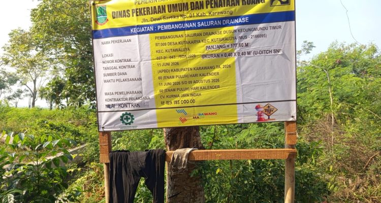 Caption : Papan informasi proyek pembangunan saluran drainase U-Ditch di Dusun Kedungmundu Timur, Desa Kutakarya, Kecamatan Kutawaluya, Kabupaten Karawang. Proyek yang dikerjakan oleh CV Kurnia Jaya Indah dengan nilai kontrak Rp189.185.000 bersumber dari APBD Kabupaten Karawang Tahun Anggaran 2026 tersebut menjadi sorotan terkait dugaan minimnya penerapan standar Keselamatan dan Kesehatan Kerja (K3) di lapangan. Caption : Papan informasi proyek pembangunan saluran drainase U-Ditch di Dusun Kedungmundu Timur, Desa Kutakarya, Kecamatan Kutawaluya, Kabupaten Karawang. Proyek yang dikerjakan oleh CV Kurnia Jaya Indah dengan nilai kontrak Rp189.185.000 bersumber dari APBD Kabupaten Karawang Tahun Anggaran 2026 tersebut menjadi sorotan terkait dugaan minimnya penerapan standar Keselamatan dan Kesehatan Kerja (K3) di lapangan.