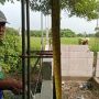 Caption: Pekerja tengah melakukan pekerjaan konstruksi pembangunan toilet SMPN 2 Jayakerta, Karawang. Terlihat pengukuran jarak pemasangan besi menggunakan meteran pada bagian struktur bangunan yang menjadi sorotan terkait dugaan ketidaksesuaian spesifikasi teknis.