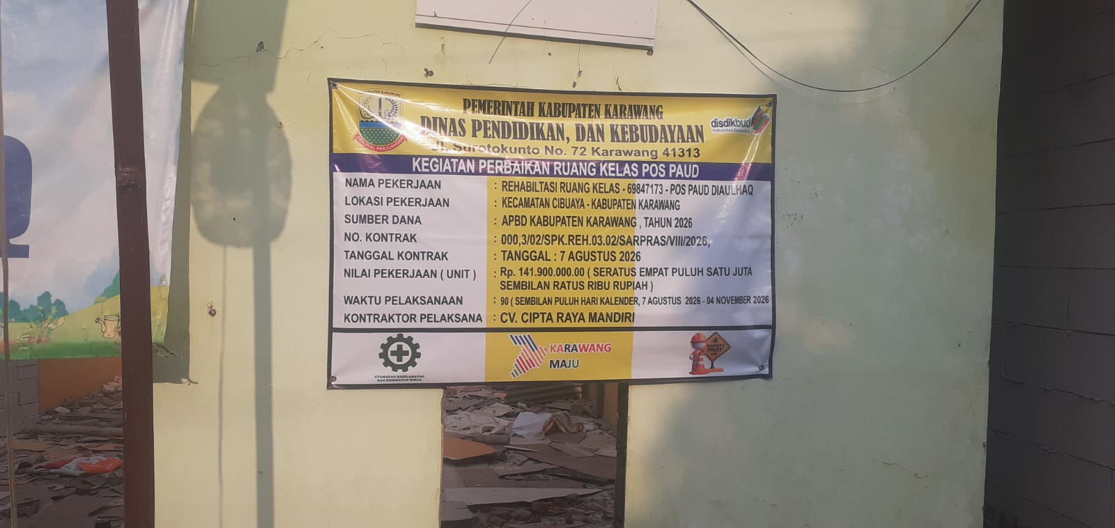 Caption: Papan informasi proyek rehabilitasi ruang kelas Pos PAUD Djaulhaq di Desa Kedungjeruk, Kecamatan Cibuaya, Kabupaten Karawang, yang mencantumkan nilai pekerjaan Rp141,9 juta bersumber dari APBD Kabupaten Karawang Tahun Anggaran 2026 dengan pelaksana CV. Cipta Raya Mandiri. Caption: Papan informasi proyek rehabilitasi ruang kelas Pos PAUD Djaulhaq di Desa Kedungjeruk, Kecamatan Cibuaya, Kabupaten Karawang, yang mencantumkan nilai pekerjaan Rp141,9 juta bersumber dari APBD Kabupaten Karawang Tahun Anggaran 2026 dengan pelaksana CV. Cipta Raya Mandiri.