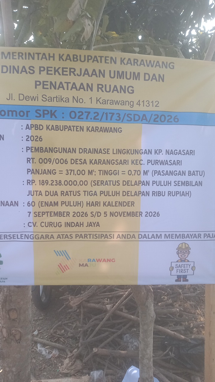 Caption: Papan informasi proyek pembangunan drainase lingkungan di Kampung Nagasari RT 009/RW 006, Desa Karangsari, Kecamatan Purwasari, Kabupaten Karawang. Proyek bersumber dari APBD Kabupaten Karawang Tahun Anggaran 2026 dengan nilai kontrak Rp189.238.000, panjang pekerjaan 371 meter dan tinggi 0,70 meter. Pelaksanaan dikerjakan CV. Curug Indah Jaya Diduga Proyek Drainase Karangsari Rp189 Juta Disorot, Pekerjaan Diduga Tak Sesuai Teknis
