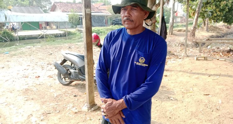 Caption: Ketua Gapoktan Desa Sukasari, Endang, saat berada di sekitar area persawahan yang terdampak kekeringan. Kondisi tersebut membuat sekitar 100 hektare lahan pertanian terancam gagal tanam dan petani berharap bantuan pompa air dari pemerintah.