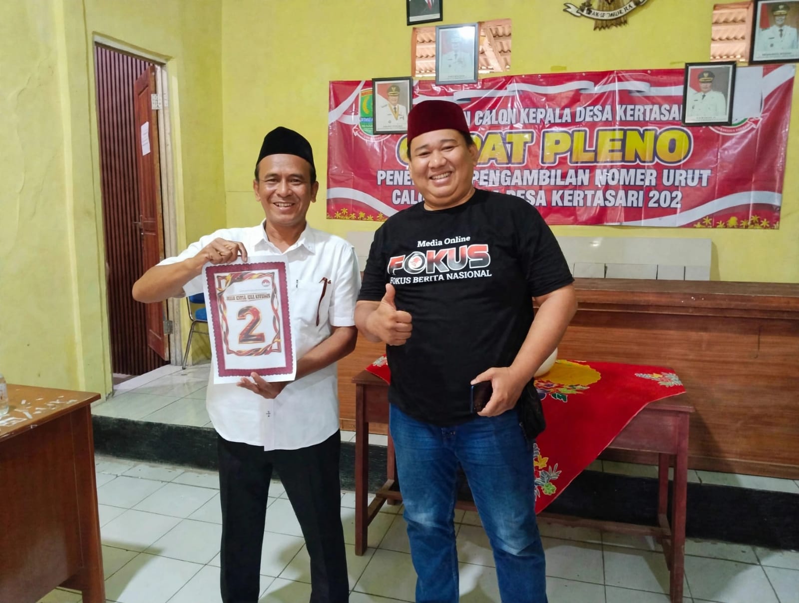 Caption: Kuwu Apud menunjukkan nomor urut 2 usai penetapan nomor urut calon Kepala Desa Kertasari, Kecamatan Rengasdengklok, Kabupaten Karawang, Kamis (15/10/2026). Dalam kesempatan tersebut, Kuwu Apud berfoto bersama salah satu tokoh pemuda sebagai bagian dari rangkaian tahapan Pilkades Kertasari.